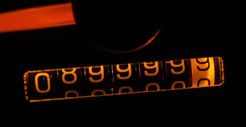 Mechanical odometer glowing orange as it rolls over from 89999 at night